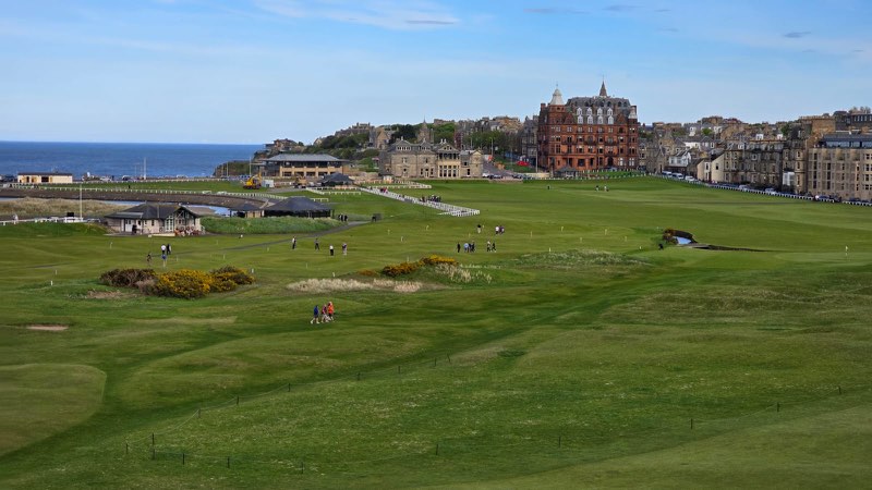 El Old Course de St Andrews desde la calle, con el edificio del R&A y el mar al fondo.